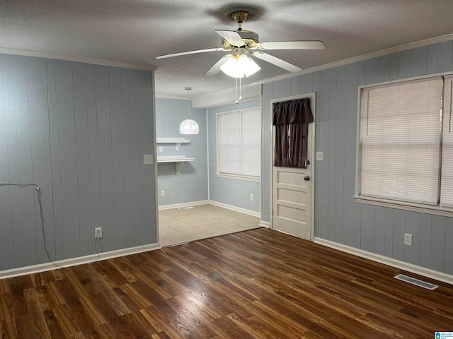 empty room featuring ceiling fan, crown molding, a textured ceiling, and dark tile patterned floors