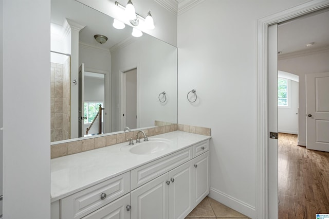 bathroom featuring baseboards, ornamental molding, and vanity