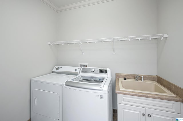 washroom featuring a sink, crown molding, cabinet space, and washer and clothes dryer