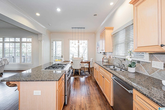 kitchen with light brown cabinets, dark stone counters, a sink, dark wood finished floors, and stainless steel appliances