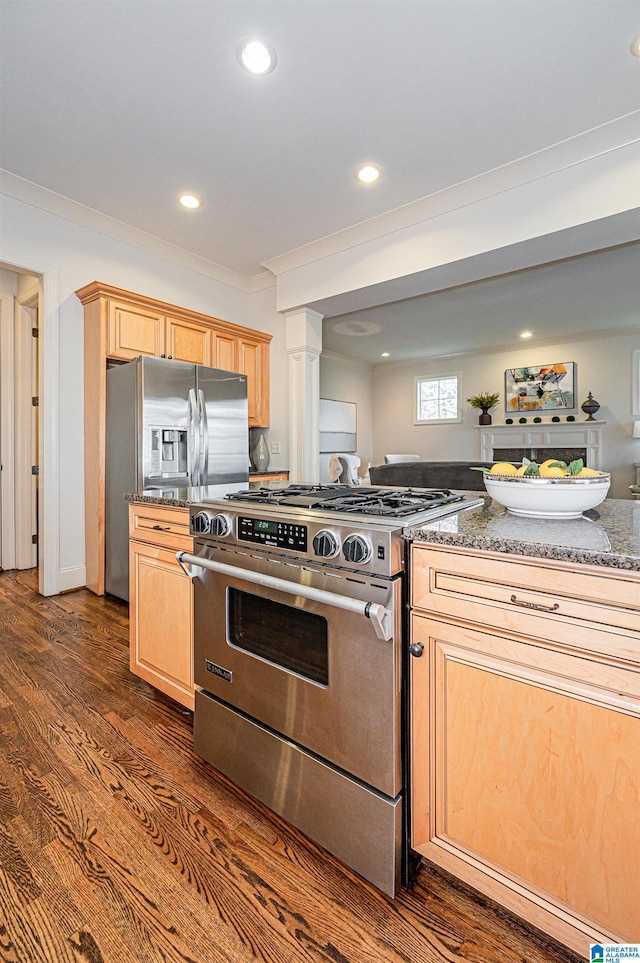 kitchen featuring light brown cabinetry, appliances with stainless steel finishes, dark wood-style floors, and dark stone counters