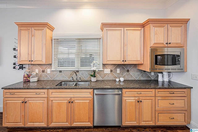 kitchen featuring stainless steel appliances, decorative backsplash, a sink, and dark stone countertops