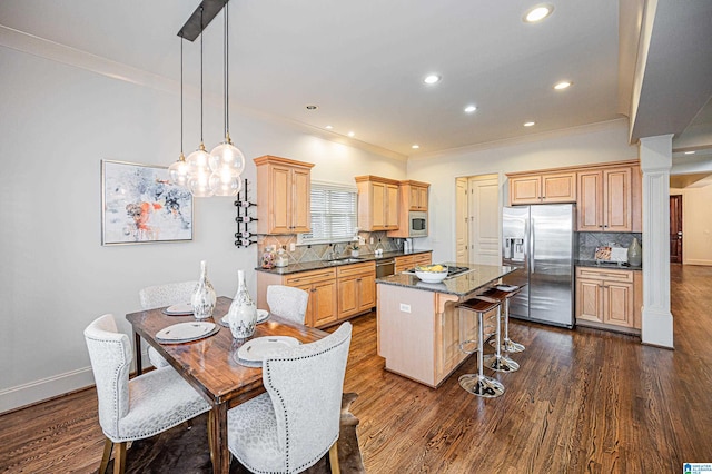 kitchen featuring crown molding, appliances with stainless steel finishes, a kitchen bar, and dark wood-style floors