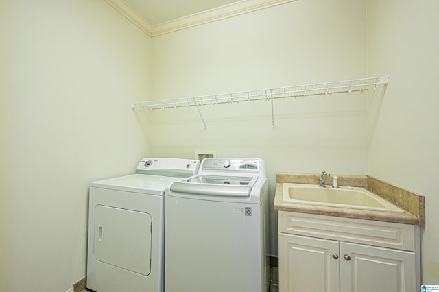 clothes washing area with crown molding, a sink, cabinet space, and washer and dryer