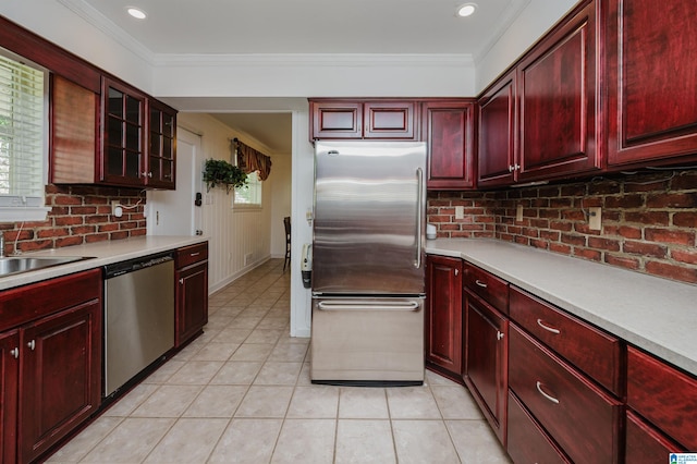 kitchen with light tile patterned flooring, stainless steel appliances, backsplash, and ornamental molding