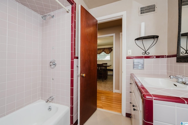 bathroom with vanity, tile walls, tiled shower / bath, and hardwood / wood-style floors