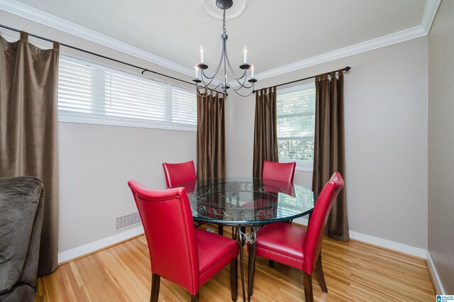 dining area with an inviting chandelier, light wood-type flooring, and ornamental molding