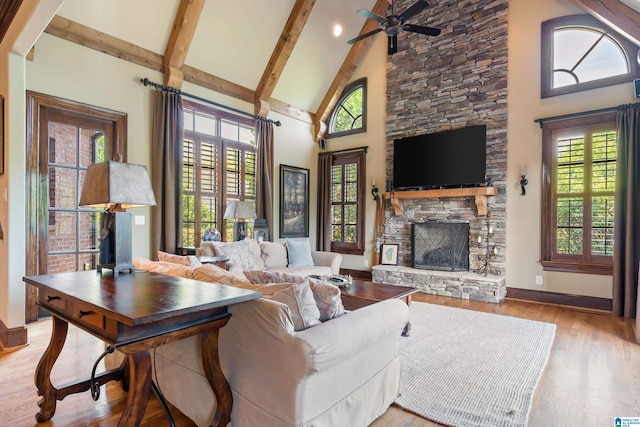 living room featuring a fireplace, light hardwood / wood-style floors, beamed ceiling, and high vaulted ceiling