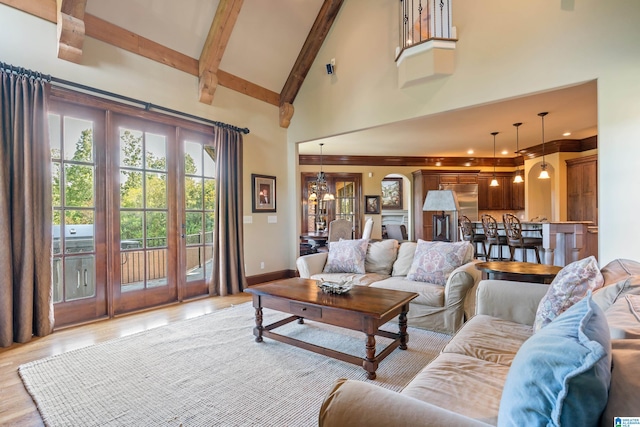 living room with a notable chandelier, high vaulted ceiling, and light wood-type flooring