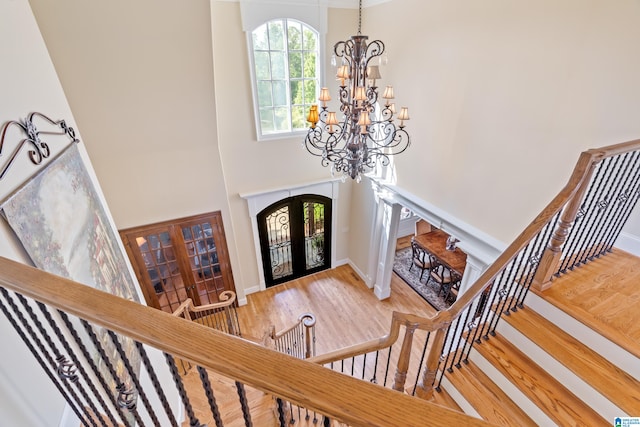 foyer entrance with hardwood / wood-style flooring, french doors, a high ceiling, and an inviting chandelier