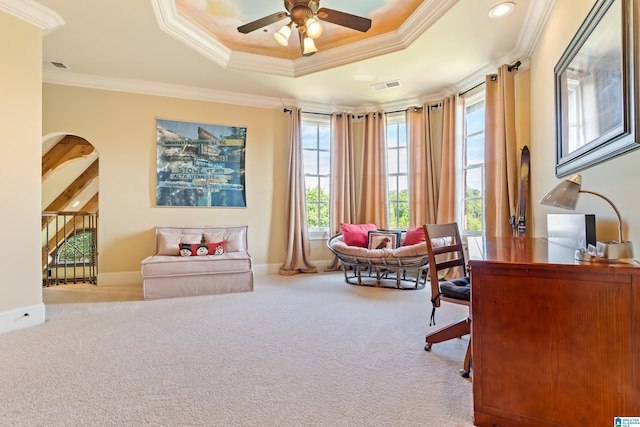 carpeted home office featuring ceiling fan, crown molding, and a tray ceiling