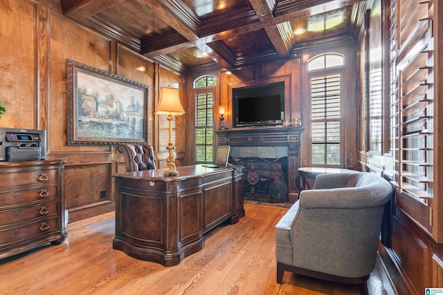 office area with beam ceiling, wooden walls, light hardwood / wood-style floors, coffered ceiling, and a fireplace