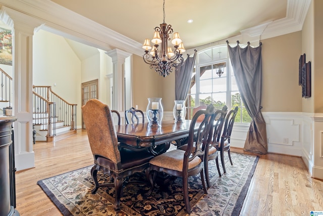 dining room featuring a notable chandelier, crown molding, ornate columns, and light wood-type flooring