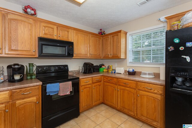 kitchen with brown cabinets, black appliances, and a textured ceiling