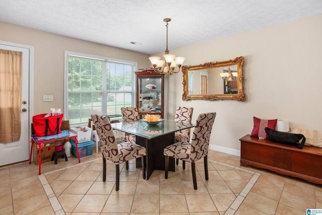 dining room featuring light tile patterned floors, a notable chandelier, baseboards, and a textured ceiling