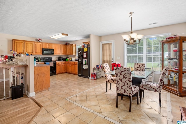 kitchen featuring a notable chandelier, black appliances, visible vents, and light tile patterned floors