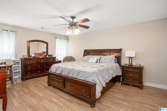 bedroom with multiple windows, baseboards, and light wood-style floors