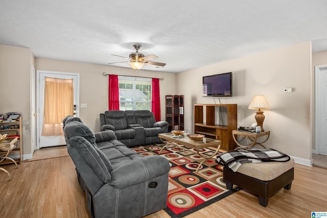 living area featuring a ceiling fan, baseboards, and wood finished floors