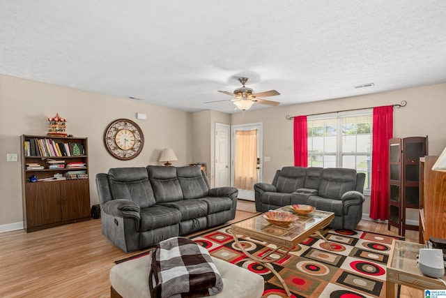 living room featuring a ceiling fan, a textured ceiling, baseboards, and wood finished floors
