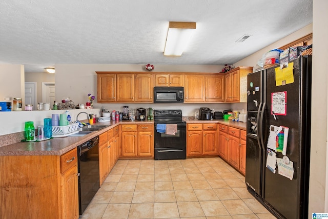 kitchen featuring visible vents, black appliances, a sink, and brown cabinetry