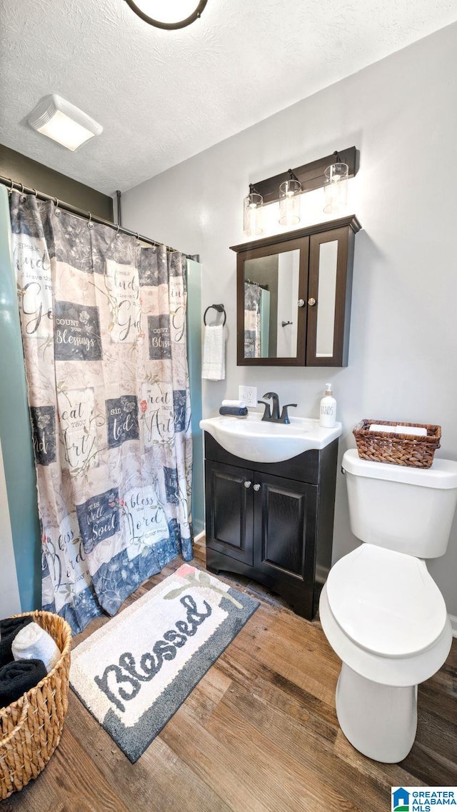 bathroom with hardwood / wood-style flooring, vanity, curtained shower, and a textured ceiling