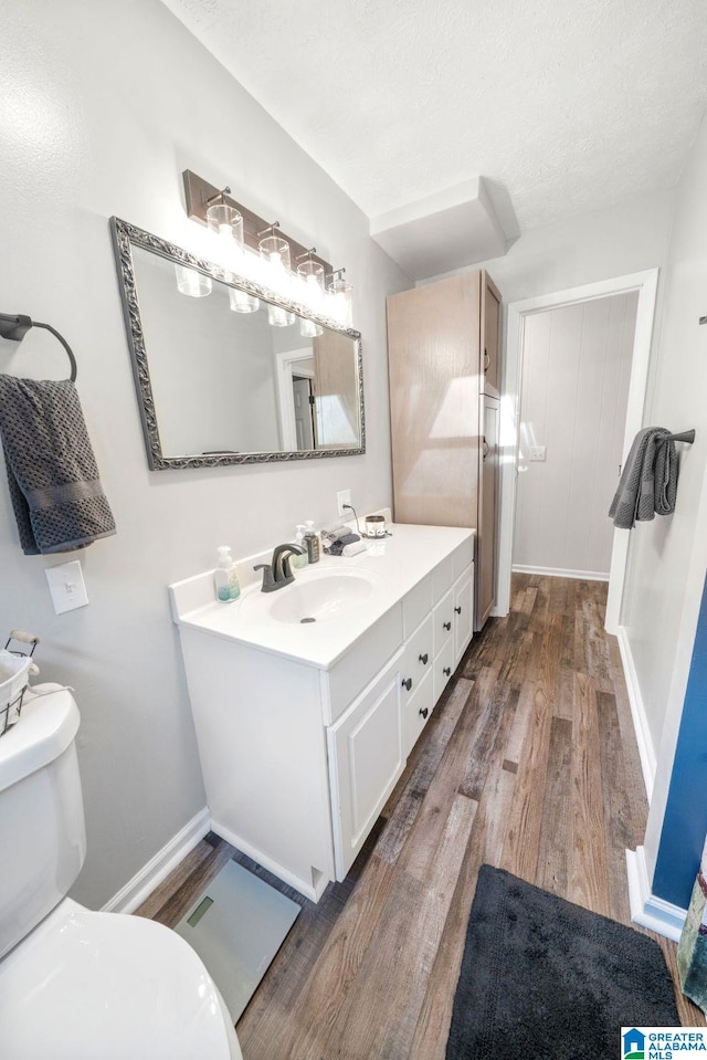 bathroom with hardwood / wood-style flooring, vanity, a textured ceiling, and toilet