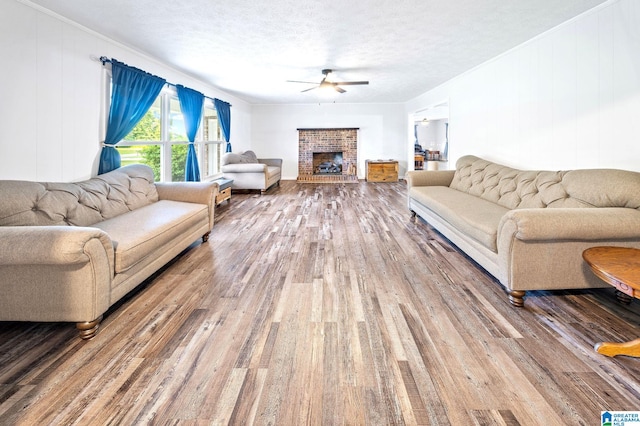 living room featuring ceiling fan, hardwood / wood-style floors, a fireplace, and a textured ceiling