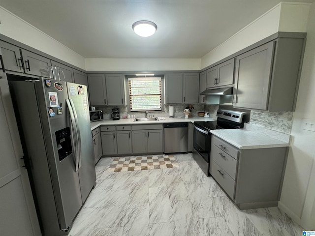 kitchen with appliances with stainless steel finishes, light tile patterned floors, decorative backsplash, and sink