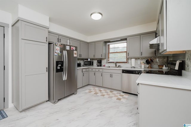 kitchen featuring sink, backsplash, gray cabinets, and stainless steel appliances