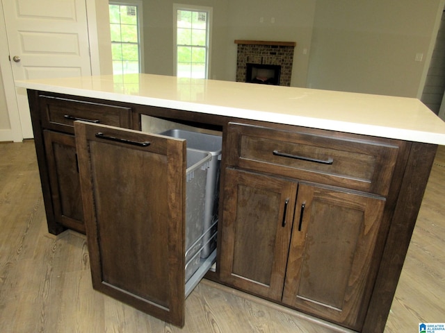 kitchen featuring light hardwood / wood-style flooring, dark brown cabinetry, and a brick fireplace