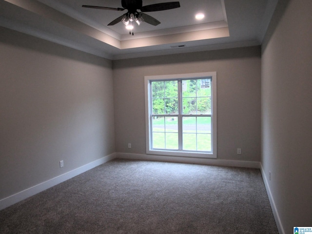 carpeted empty room with ceiling fan and a raised ceiling