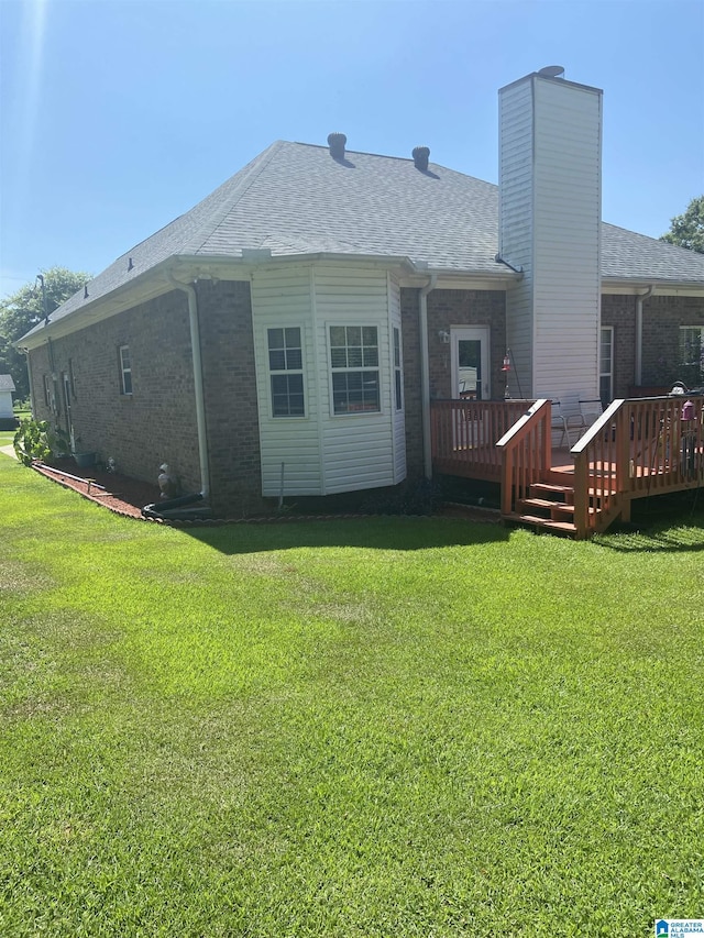 rear view of house with a wooden deck and a lawn