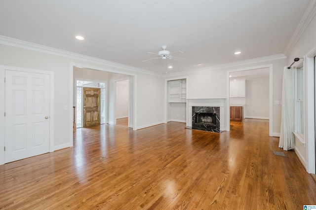 unfurnished living room featuring ceiling fan, ornamental molding, a fireplace, and hardwood / wood-style flooring