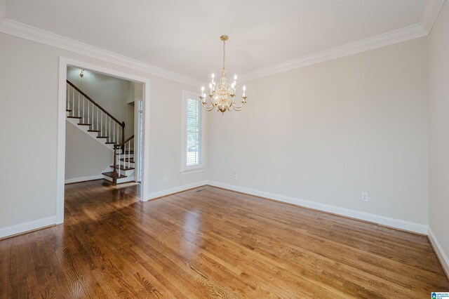 unfurnished room with an inviting chandelier, ornamental molding, and hardwood / wood-style floors