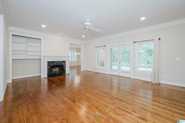 unfurnished living room featuring ceiling fan, a premium fireplace, ornamental molding, and light hardwood / wood-style floors