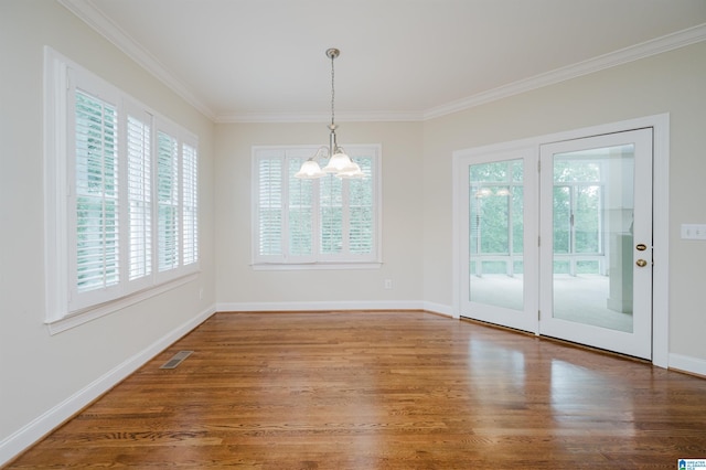 unfurnished dining area featuring hardwood / wood-style floors, ornamental molding, and a chandelier