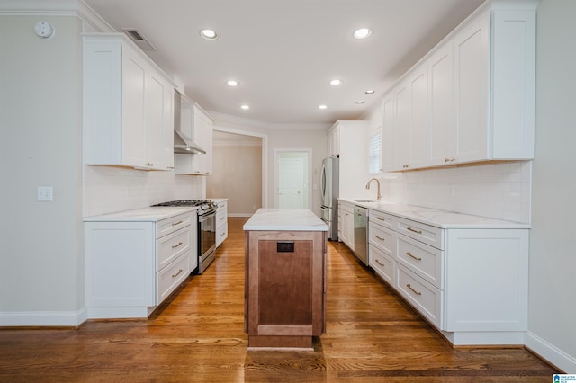 kitchen with appliances with stainless steel finishes, sink, white cabinetry, and a center island