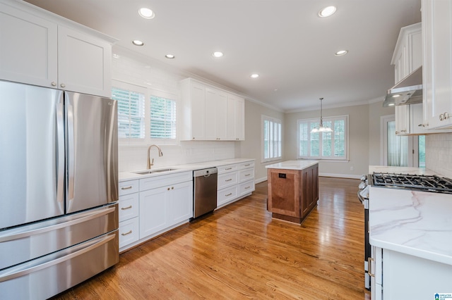 kitchen with white cabinetry, ventilation hood, stainless steel appliances, sink, and a center island