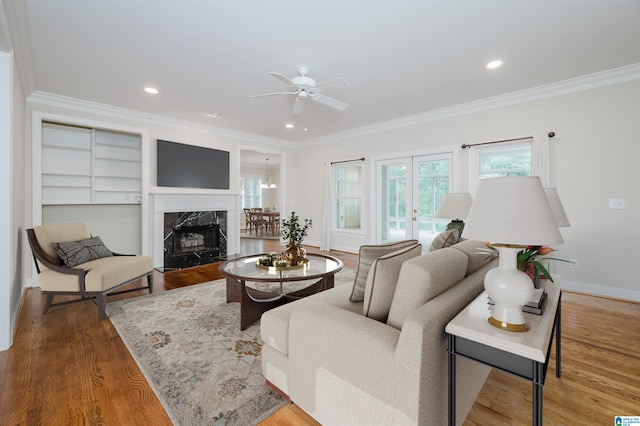 living room featuring ceiling fan, wood-type flooring, crown molding, and a fireplace