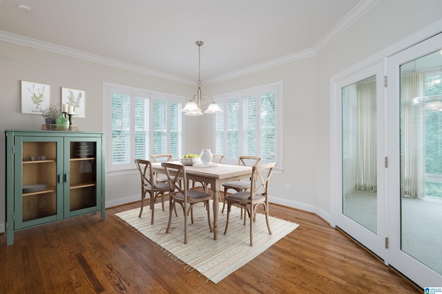 dining area featuring hardwood / wood-style floors, ornamental molding, a healthy amount of sunlight, and an inviting chandelier