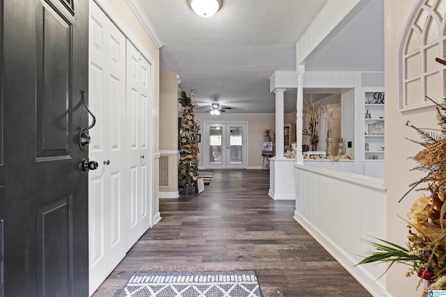 foyer featuring dark wood-type flooring, a textured ceiling, ceiling fan, and ornate columns