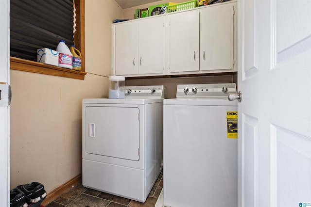 clothes washing area featuring cabinets, dark tile patterned floors, and washer and dryer