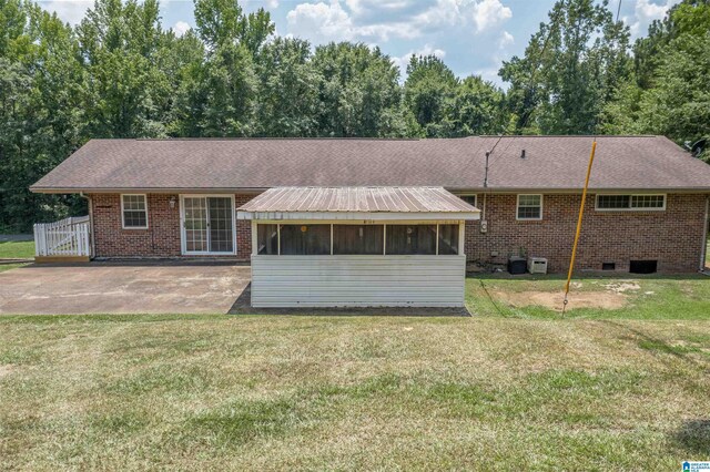 rear view of house featuring a patio area, a sunroom, and a lawn