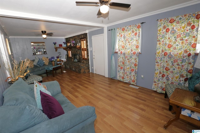 living room featuring wood-type flooring, a fireplace, ornamental molding, and ceiling fan