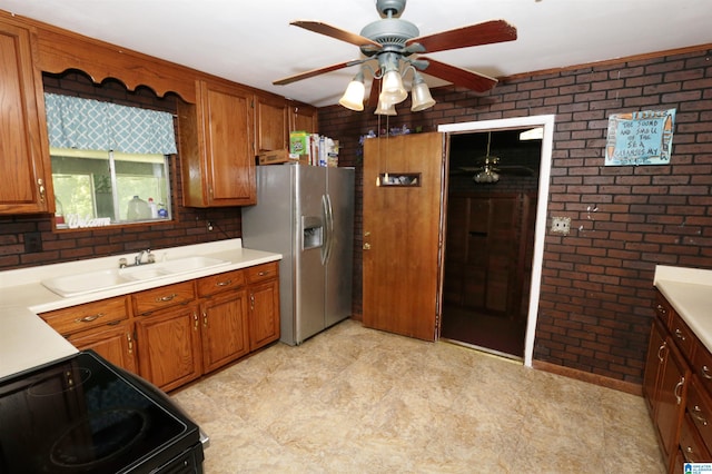 kitchen with sink, brick wall, ceiling fan, stainless steel refrigerator with ice dispenser, and electric range