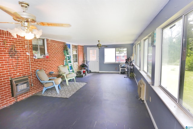 unfurnished sunroom with plenty of natural light, a wall unit AC, ceiling fan, and heating unit