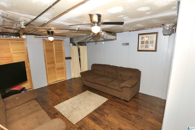 living room featuring wood walls, ceiling fan, and dark wood-type flooring