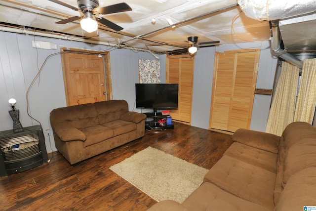 living room with wood walls, ceiling fan, and dark wood-type flooring