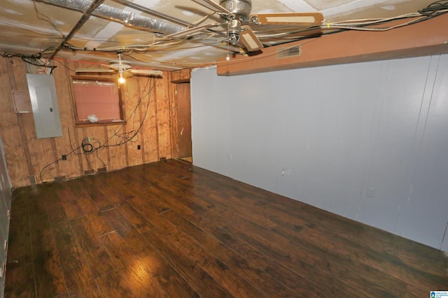 basement featuring wood walls, electric panel, and dark wood-type flooring