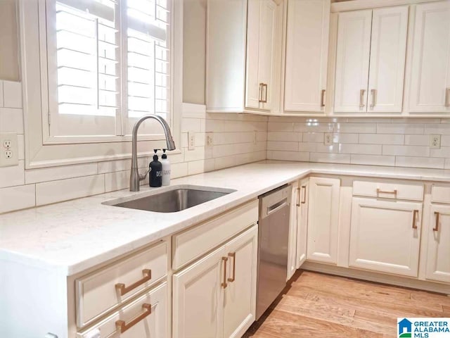 kitchen with sink, light stone counters, dishwasher, light hardwood / wood-style floors, and decorative backsplash